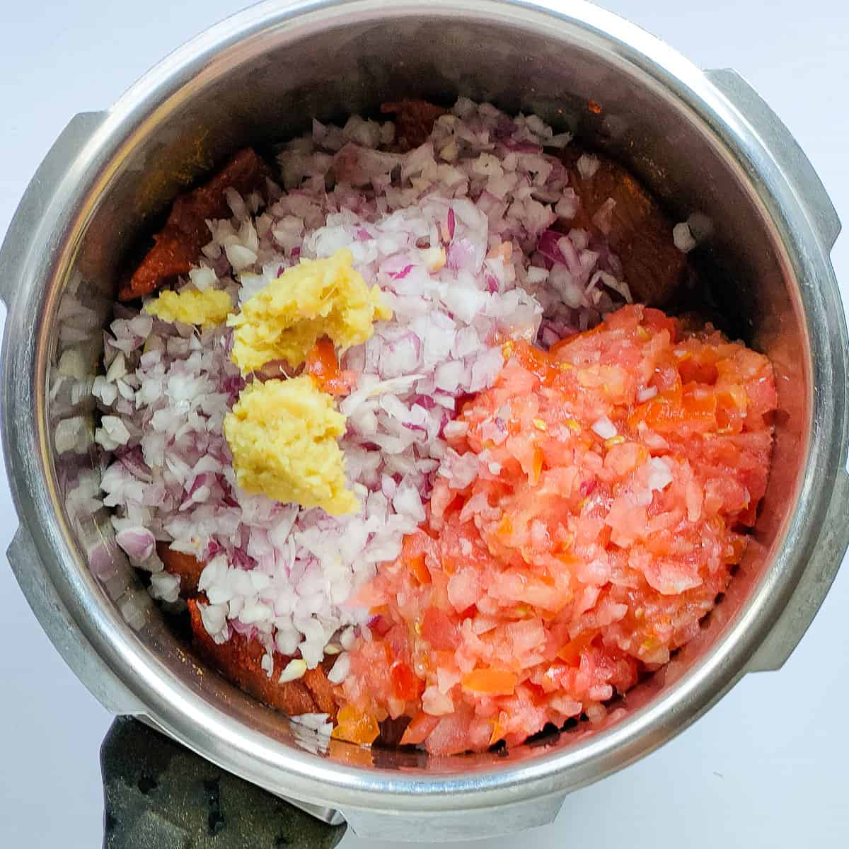 Chopped onions, tomatoes and ginger garlic paste with mutton in a pressure cooker.