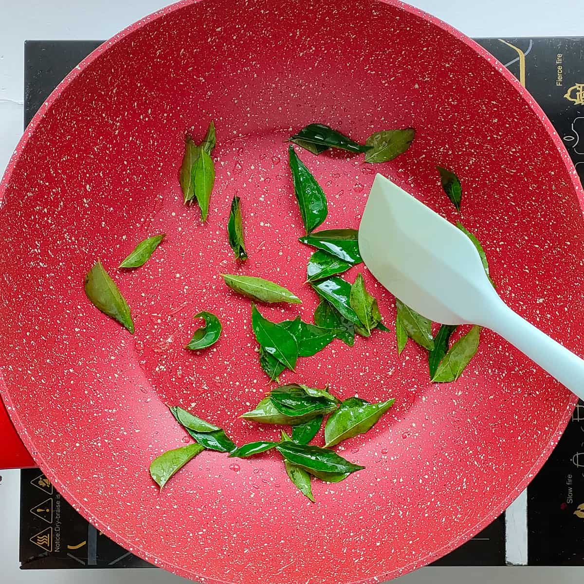 Curry leaves being roasted in a pan.