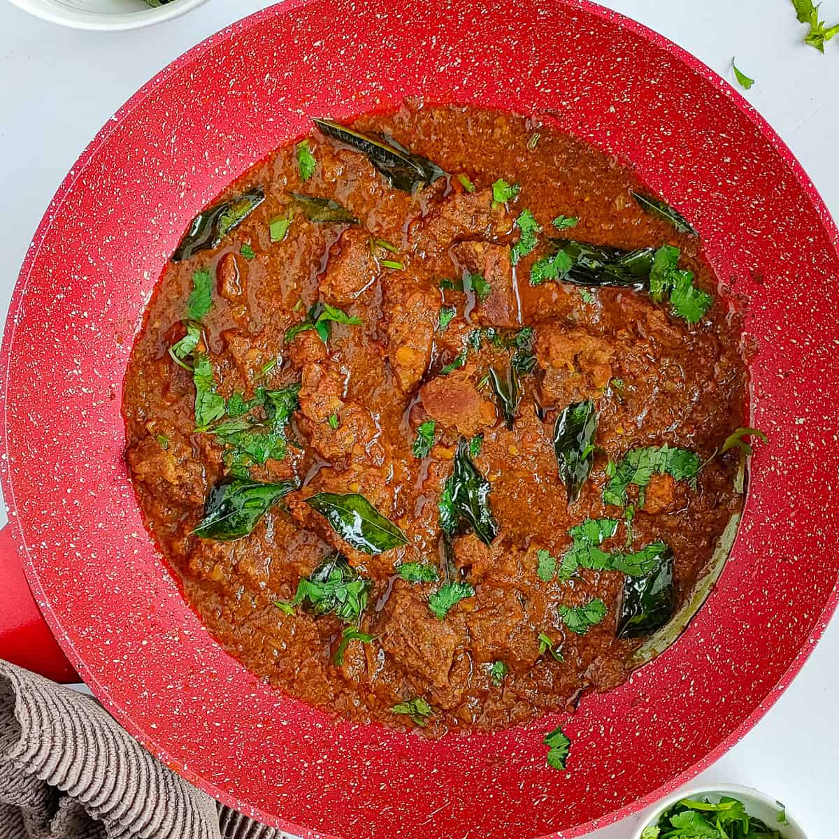 Goat masala garnished with coriander leaves and roasted curry leaves.