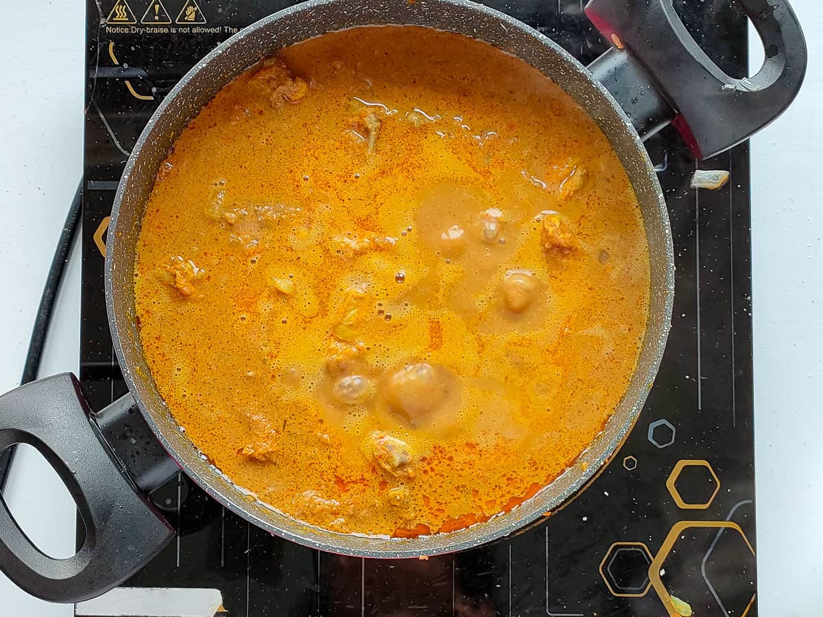 Varutharacha chicken curry simmering in a non-stick cooking pot.
