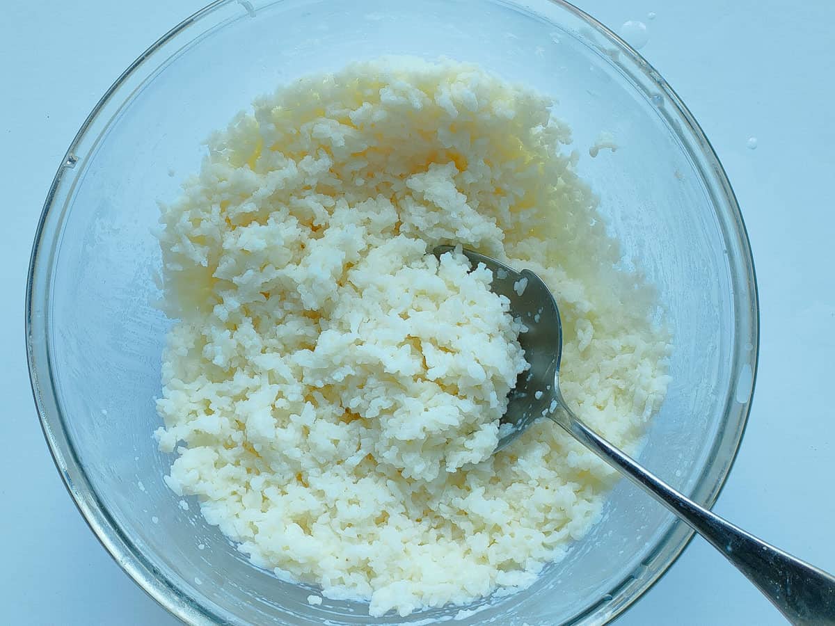 Cooked and mashed rice in a glass bowl.