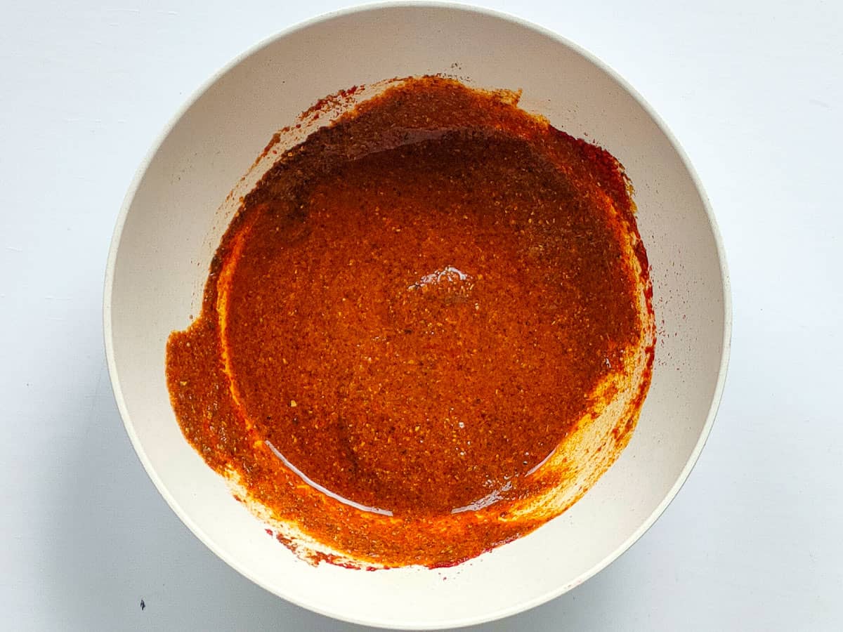 Spices mixed with water in a small white bowl.