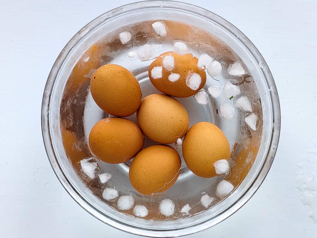 Boiled eggs in ice bath in a glass bowl.