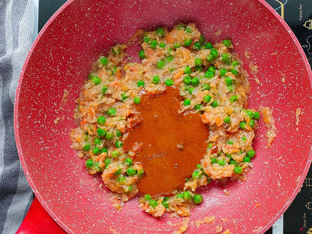 Spice paste and sauteed vegetables in a non-stick wok pan.