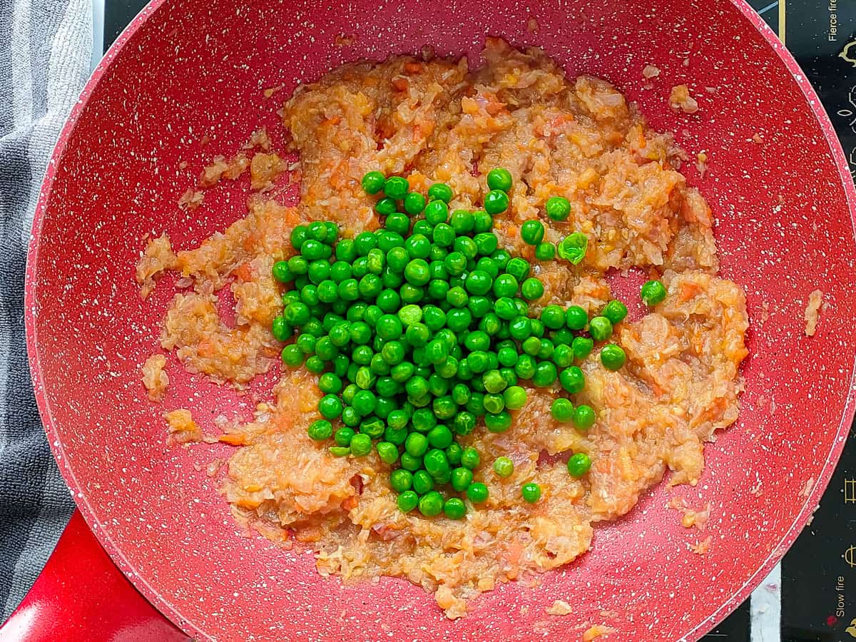 Green peas added to the gravy in a non-stick wok pan.