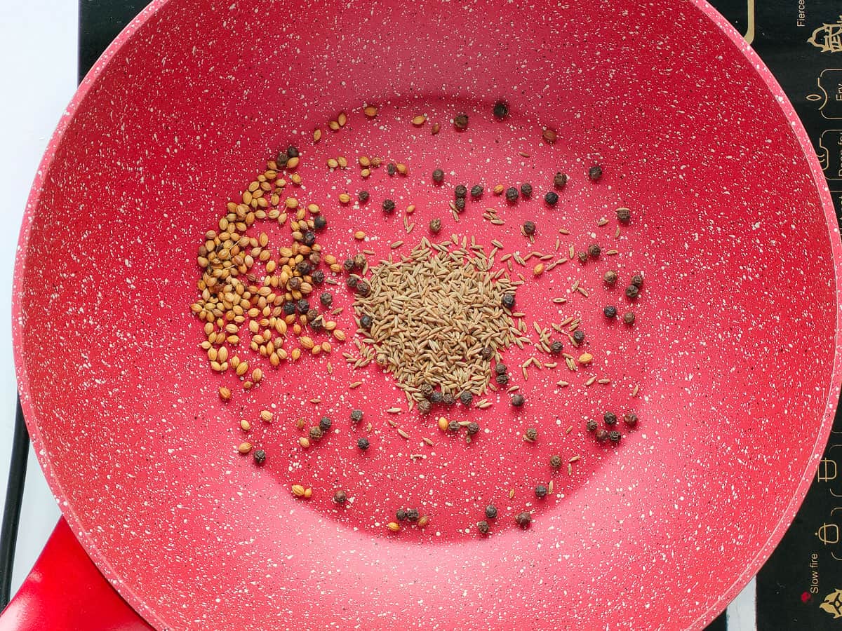 Roasted peppercorns, cumin and coriander seeds in a pan.