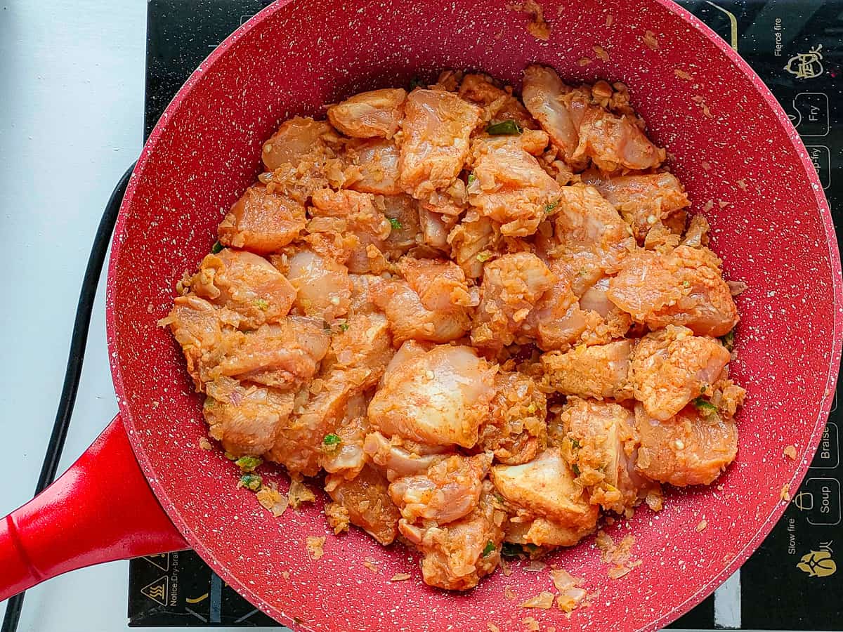 Sauteed chicken with onions and spices in a pan.