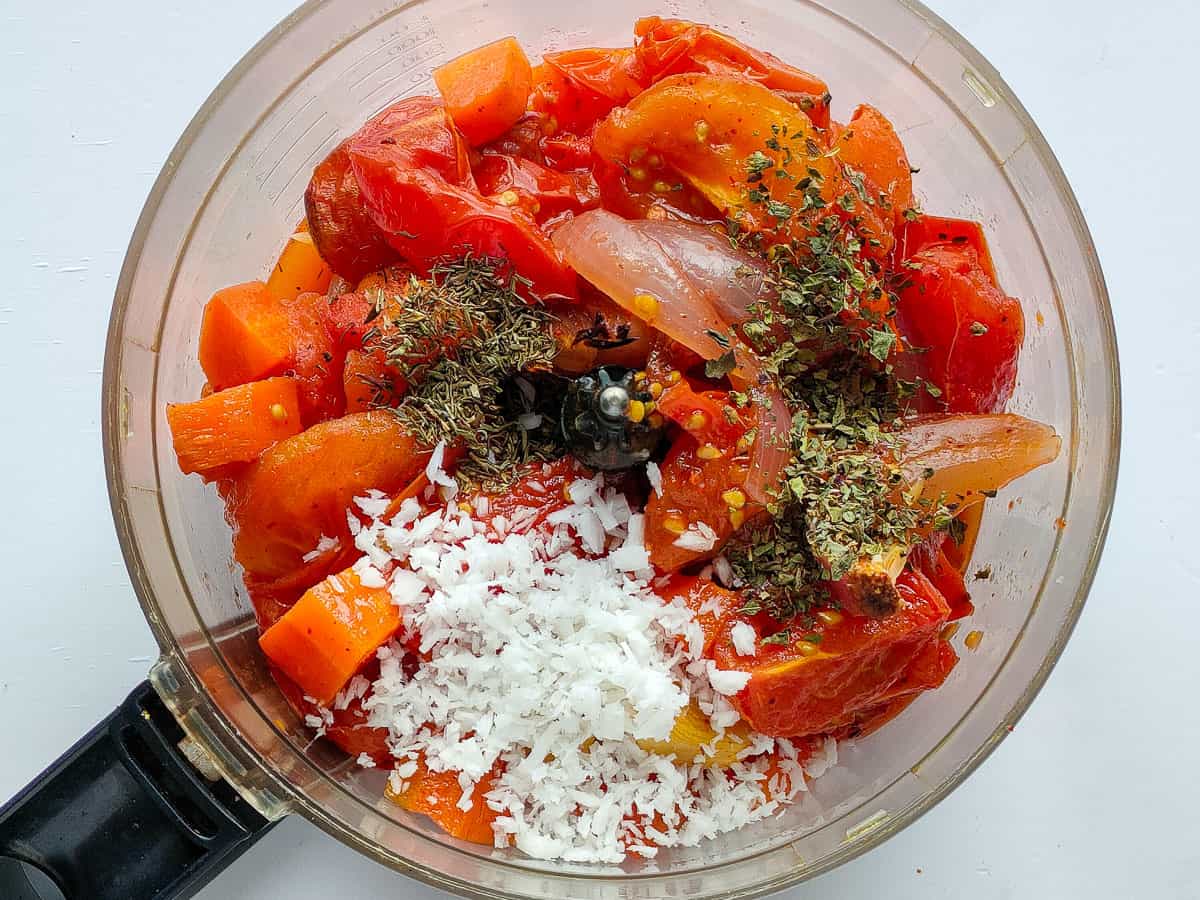 Roasted tomatoes, onions and garlic with basil, thyme and grated coconut in a food processor jar.
