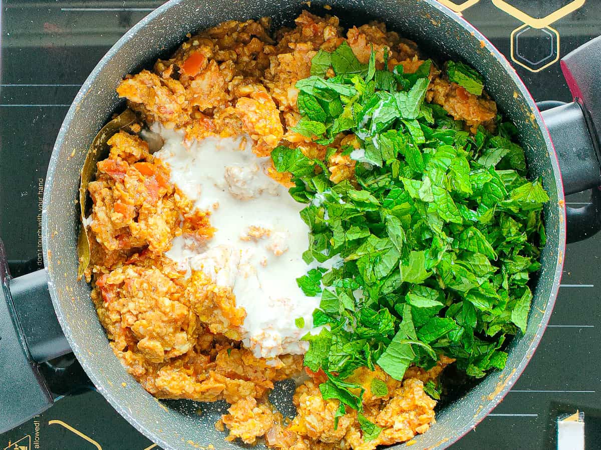 Keema chicken masala with cashew paste and mint leaves in a non-stick pot.