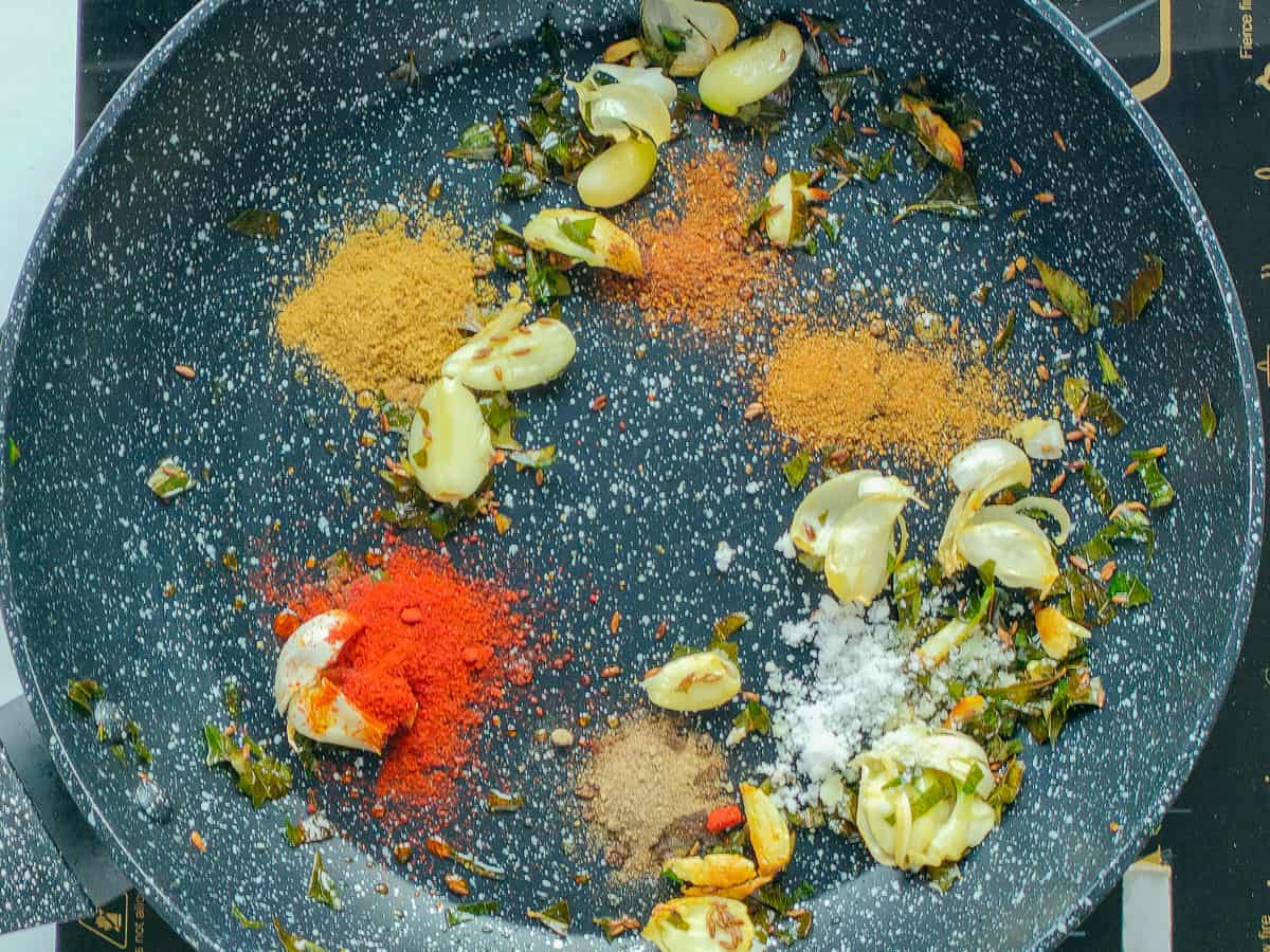 Cumin seeds, curry leaves, crushed garlic and spices in a non-stick pan.