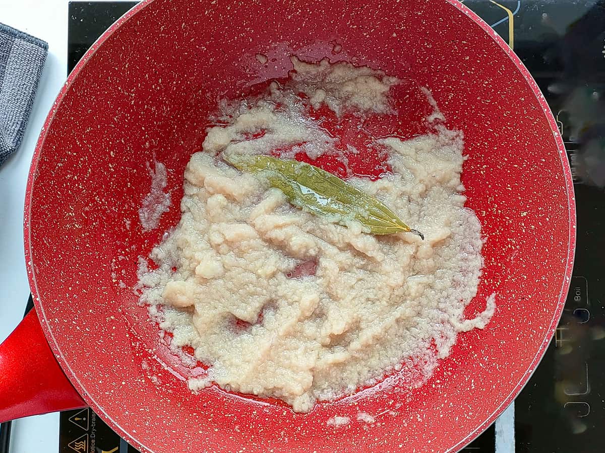 Sauteed onion paste in a pink wok pan.