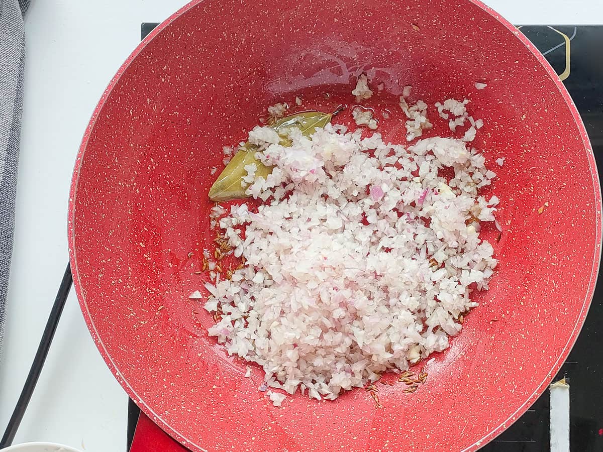 Finely chopped onions in a pink wok pan.