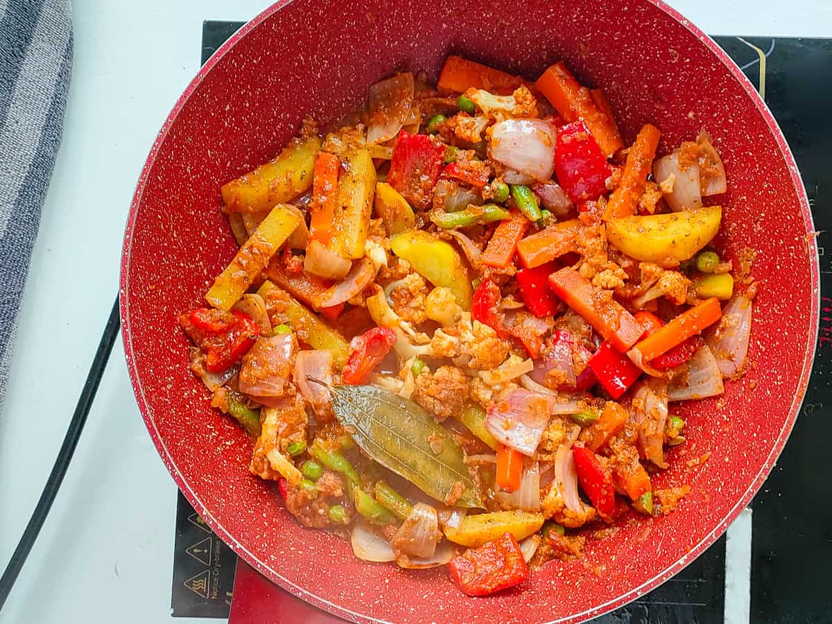 Cooked veg kadai in a pink wok pan.