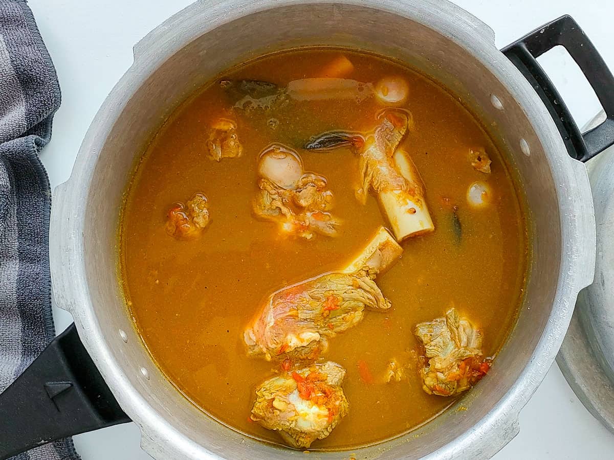 Indian mutton soup with bones and spice blend ready to be cooked in a pressure cooker.