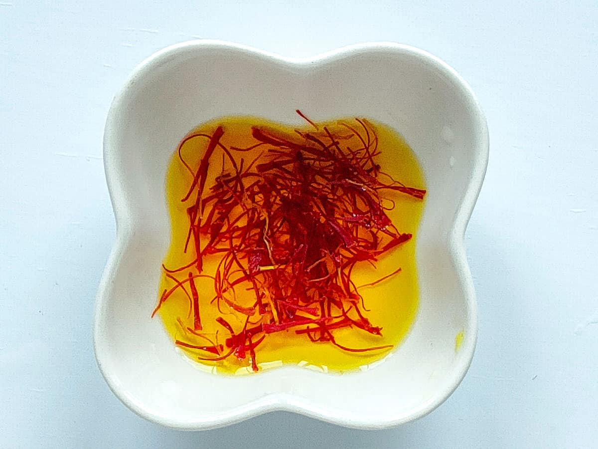 Saffron soaked in water in a small white bowl.