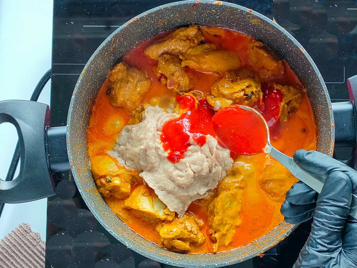 Fried onion paste and chilli paste added to chicken in a deep non-stick pot.