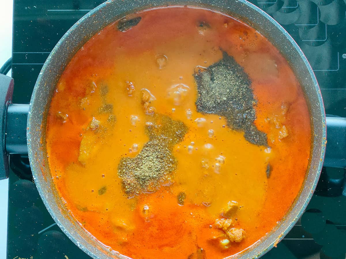 Chicken rogan josh with fennel and pepper powder in a deep non-stick pot.
