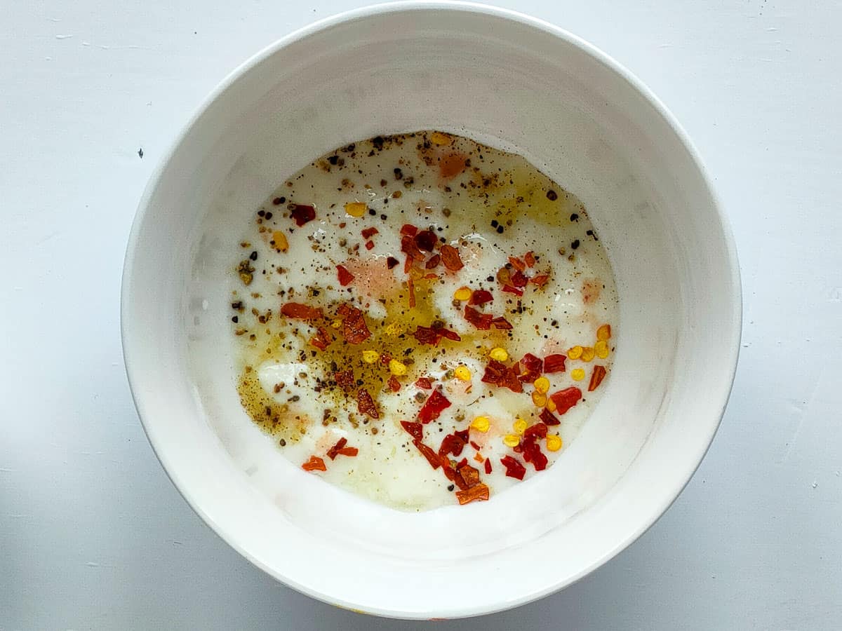 Yogurt with spices in a small white bowl.