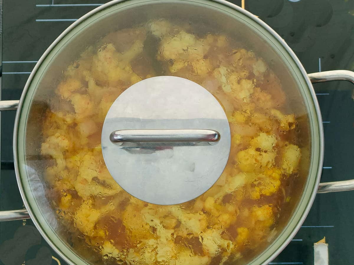 Spiced cauliflower soup simmering in a covered soup pot.