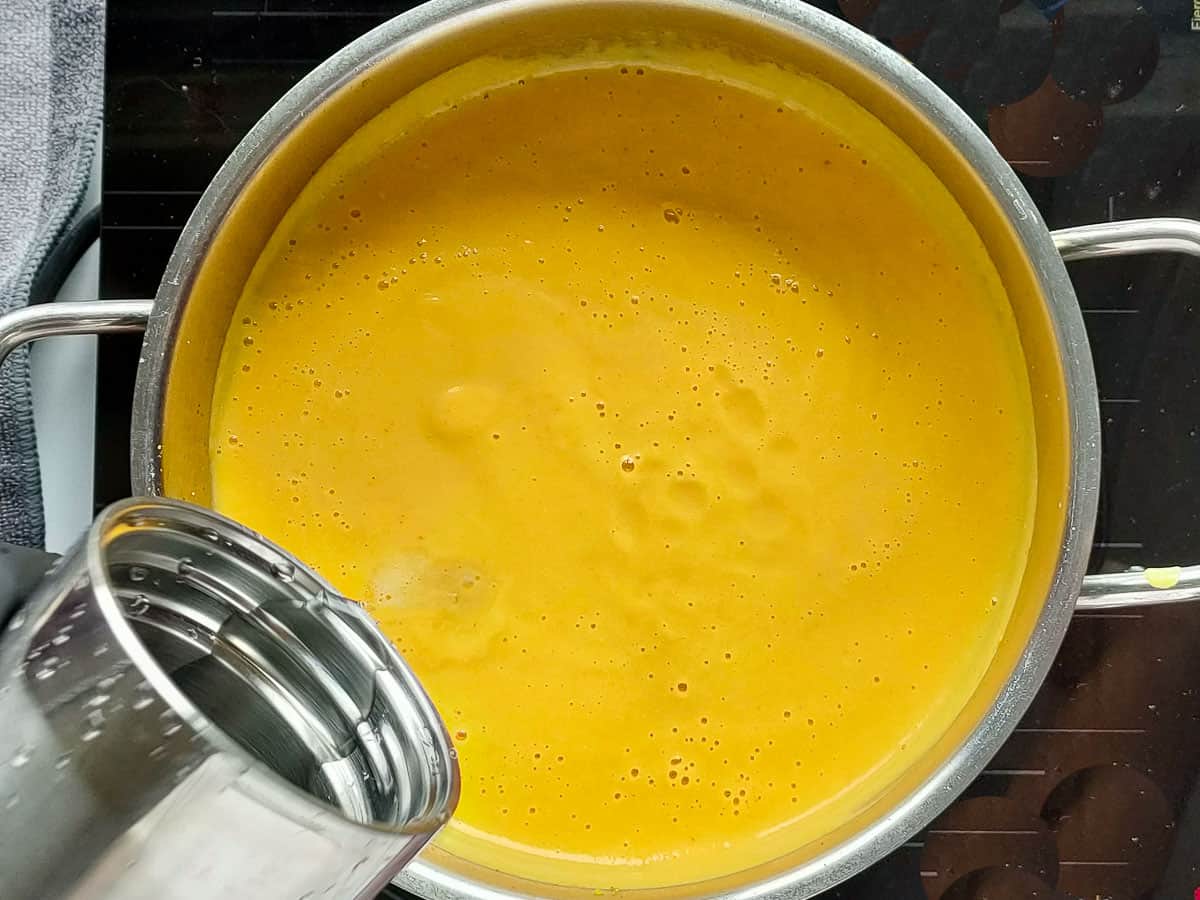 Water being added to blended cauliflower soup in a soup pot.