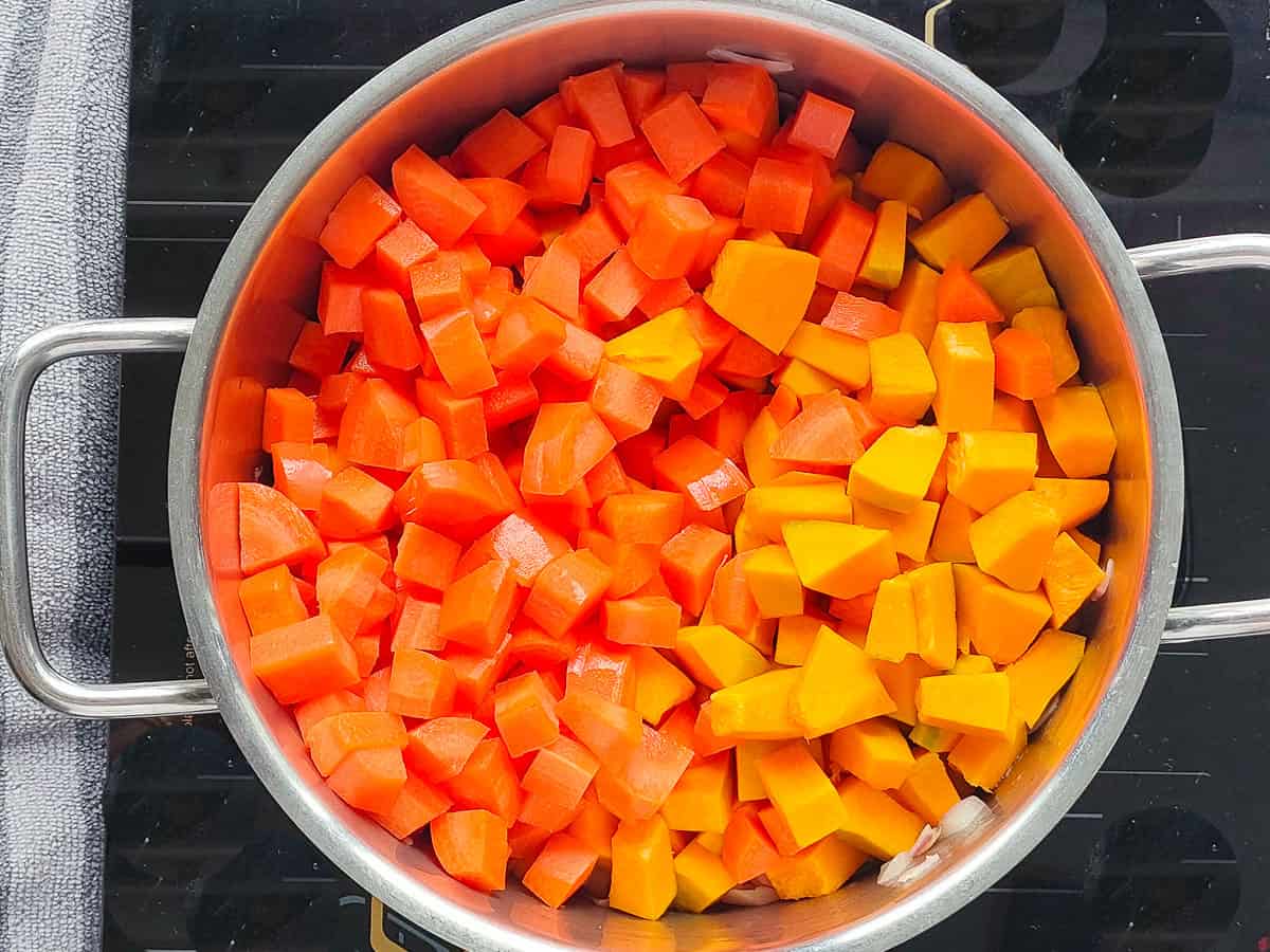 Diced pumpkin and carrots in a large pot.