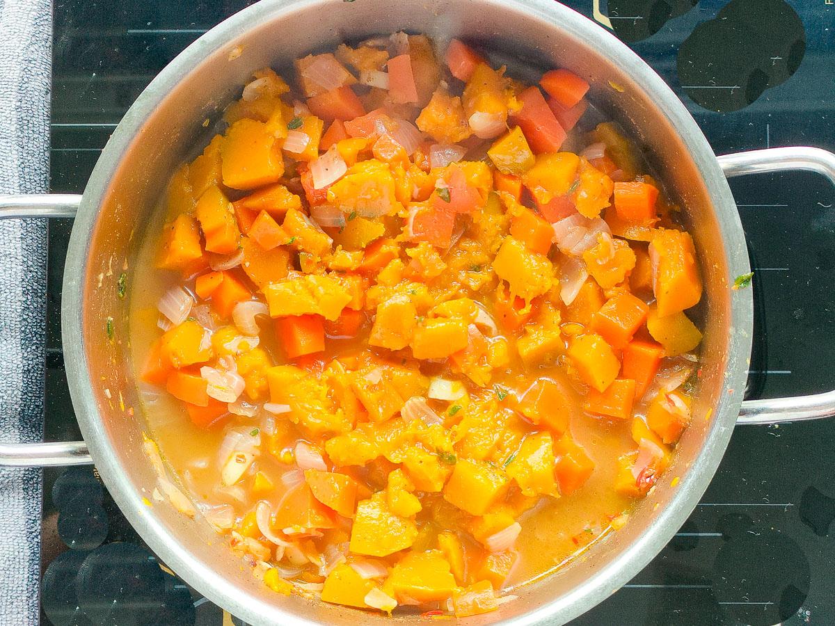 Cooked pumpkin and carrots in a large pot.