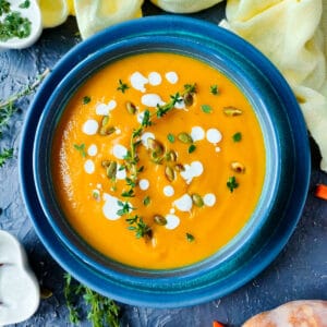 Pumpkin carrot soup in a blue bowl.