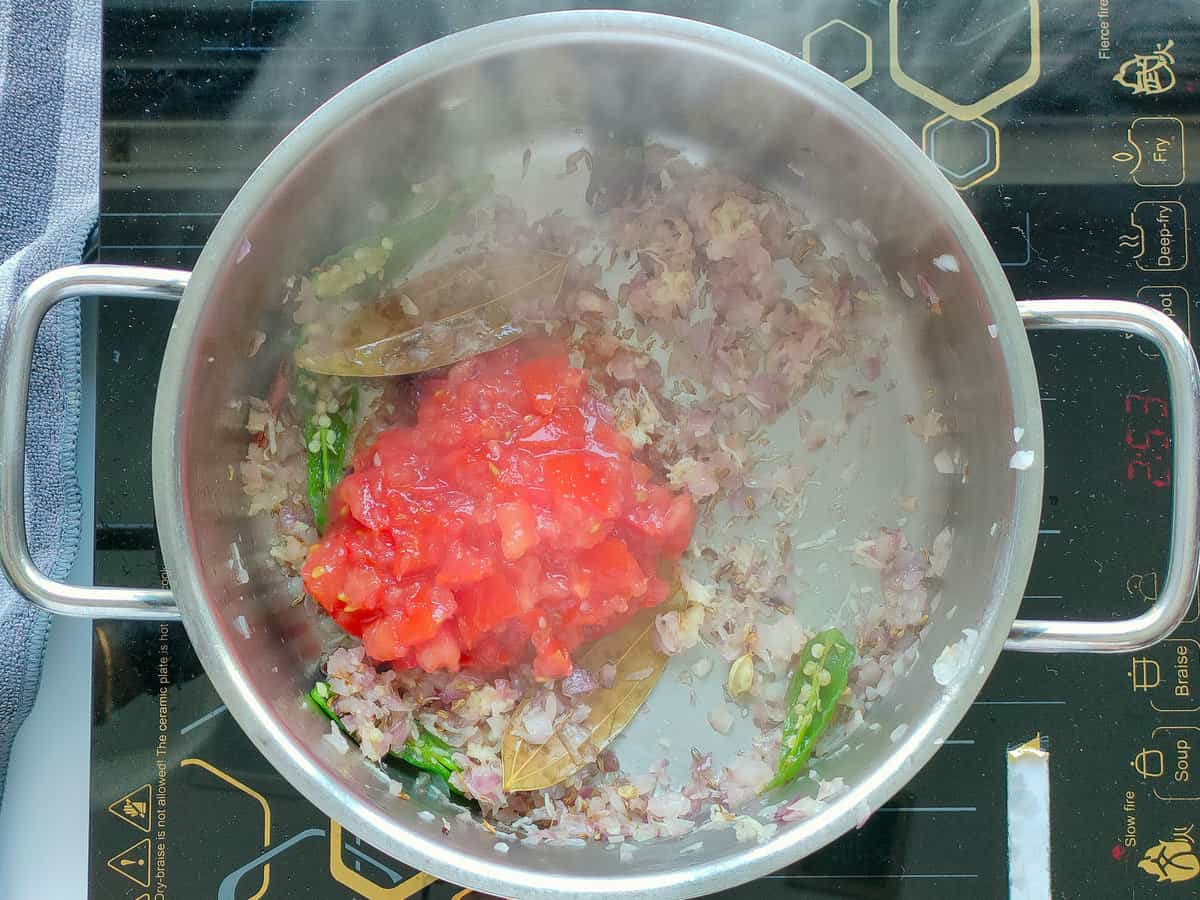 Tomatoes and sauteed onions in a large pot.