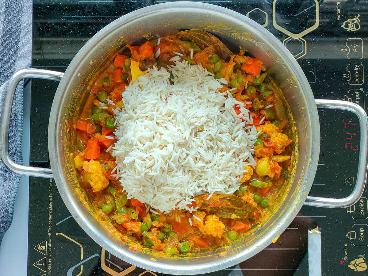 Rice added to sauteed vegetables in a large pot.