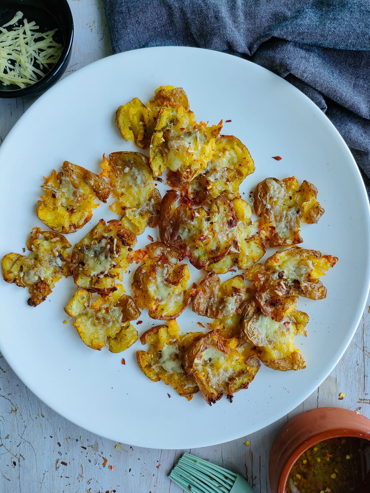 Cheesy smashed potatoes on a white plate.