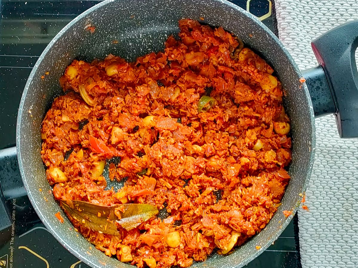 Roasted coconut and cashews with spices in a large pot.