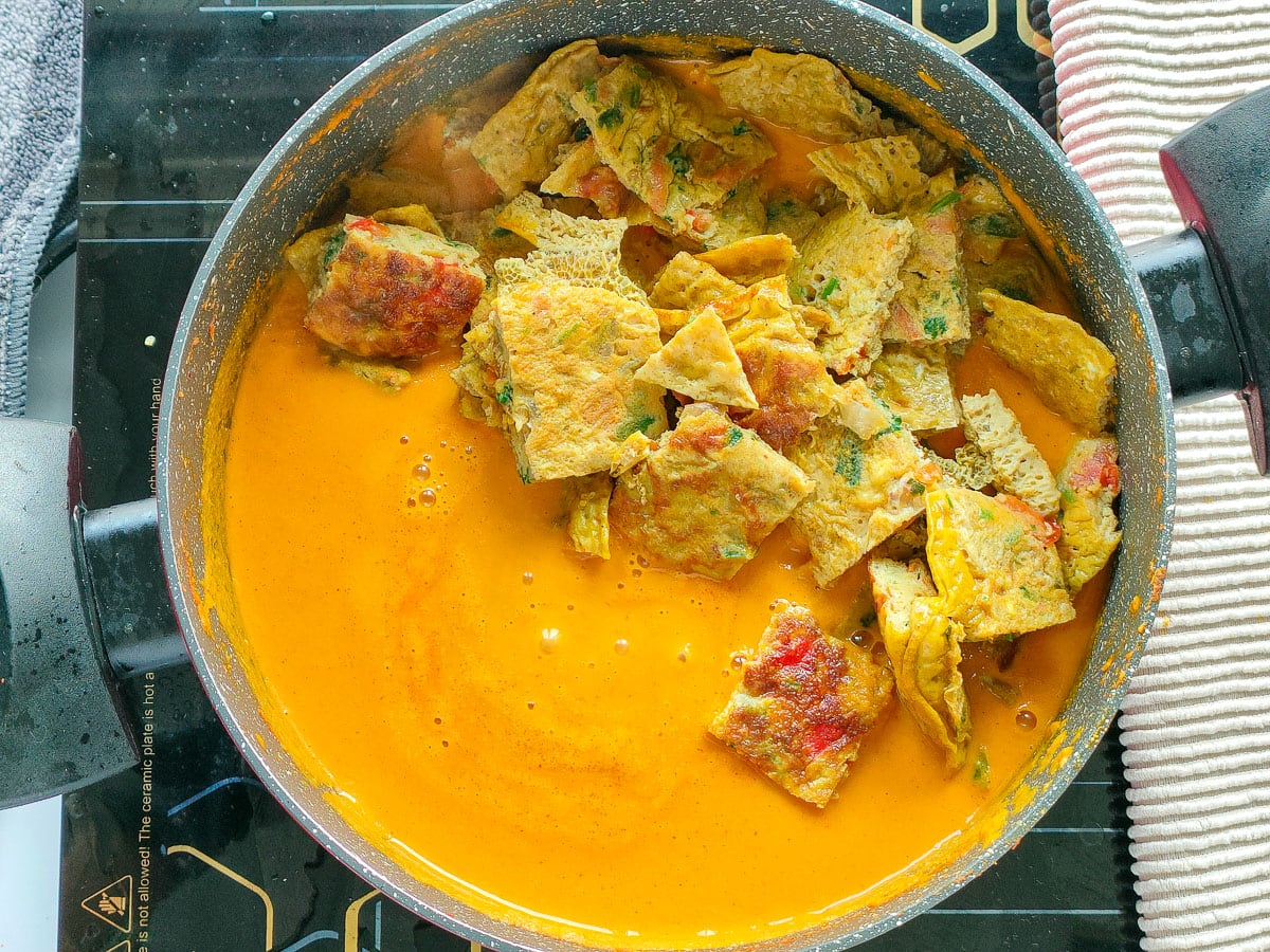 Omelette pieces in curry sauce in a pot.