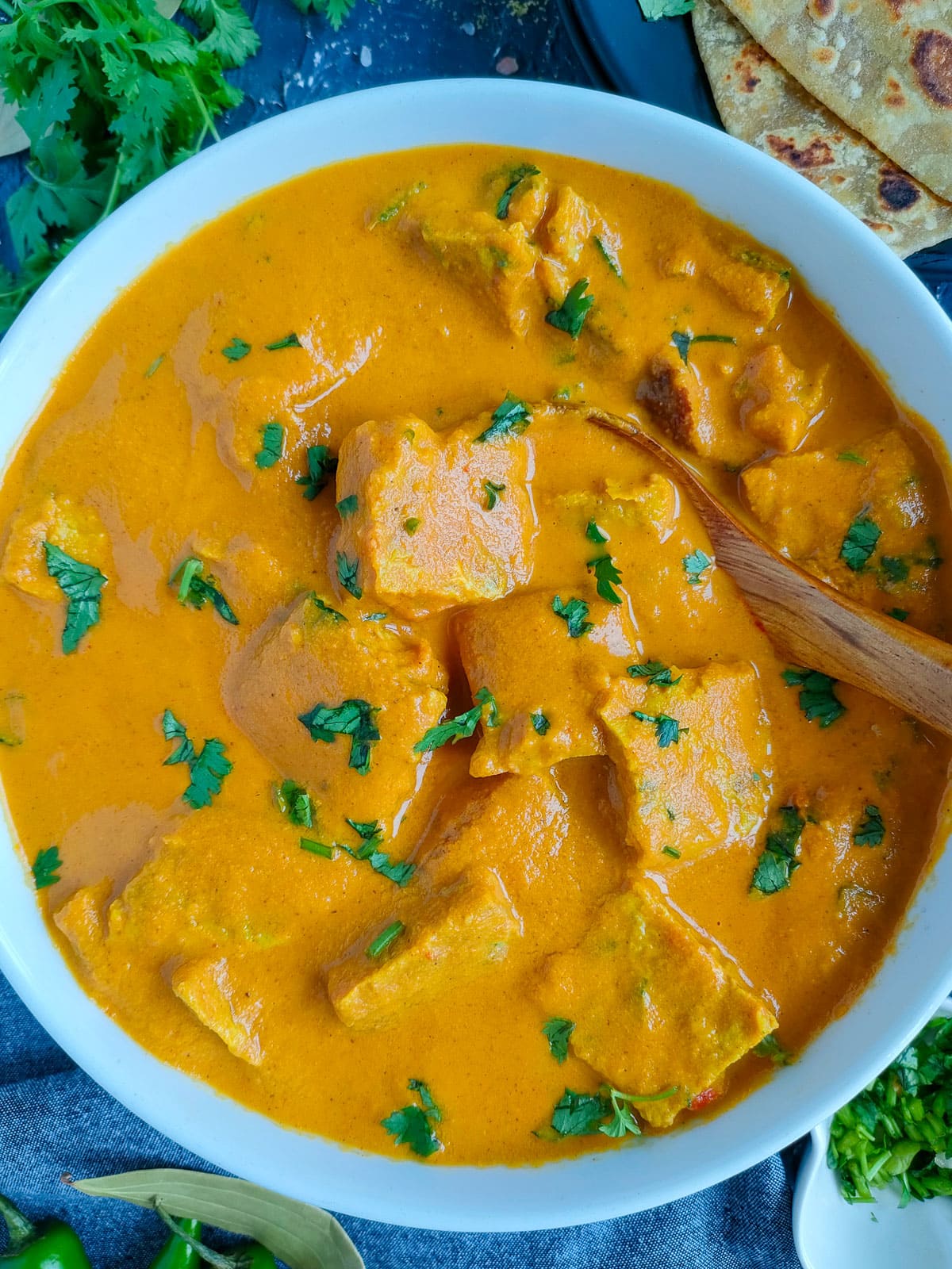 Omelette curry in a white bowl with a ladle in it.