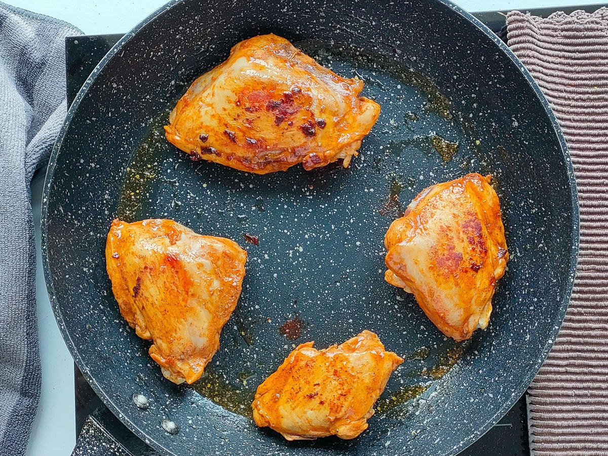 Browned chicken in a frying pan.