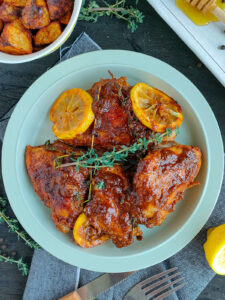 Honey garlic lemon pepper chicken garnished with thyme and caramelized lemon slices on a plate.