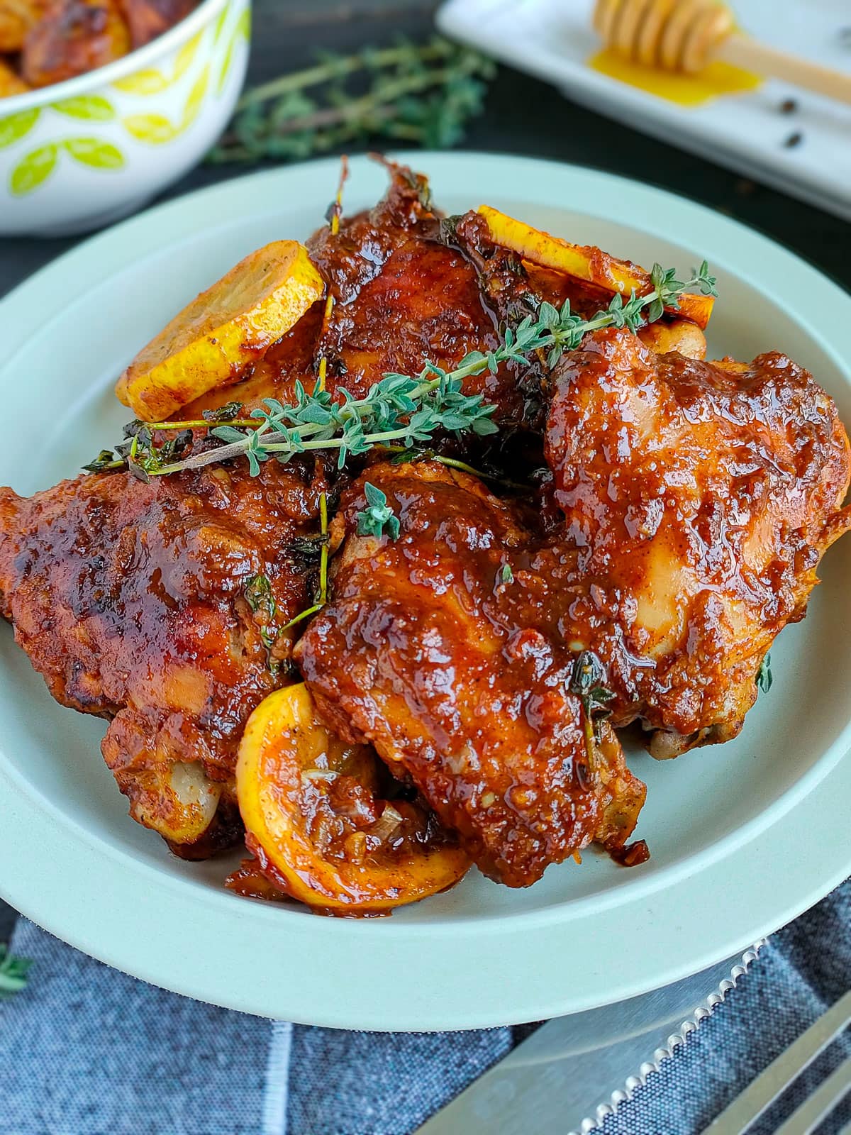 Honey garlic lemon pepper chicken thighs garnished with thyme and caramelized lemon slices on a plate.