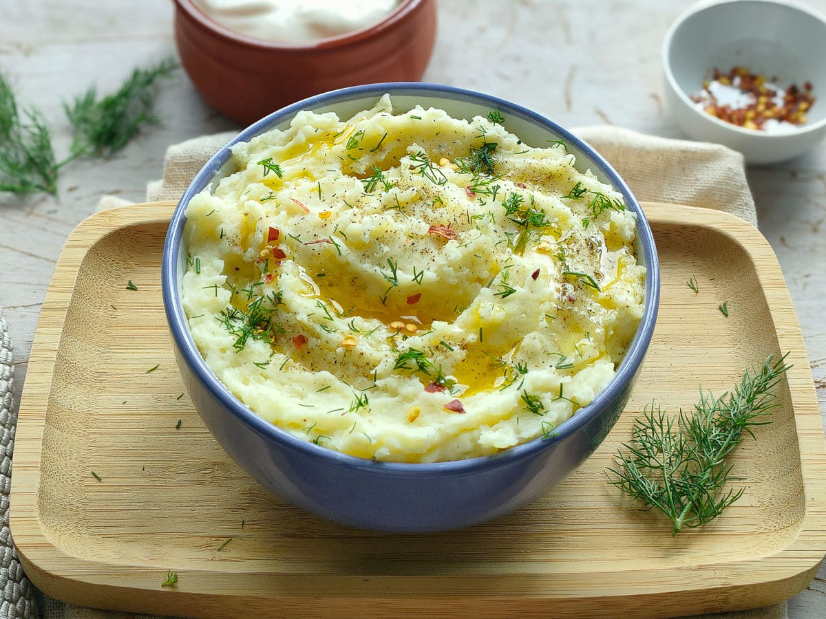 Garlic mashed potatoes with yogurt in a white and blue bowl.