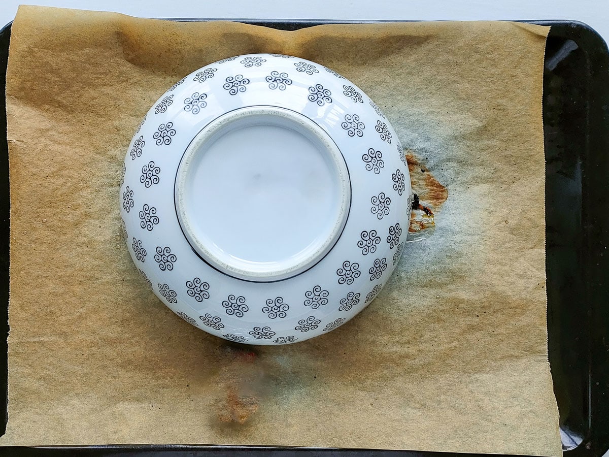 Roasted red peppers covered with a large ceramic bowl.