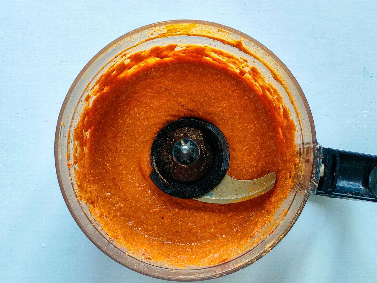 Blended feta red pepper dip in a food processor jar.