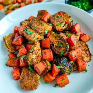 Balsamic roasted brussels sprouts and carrots on a white plate.