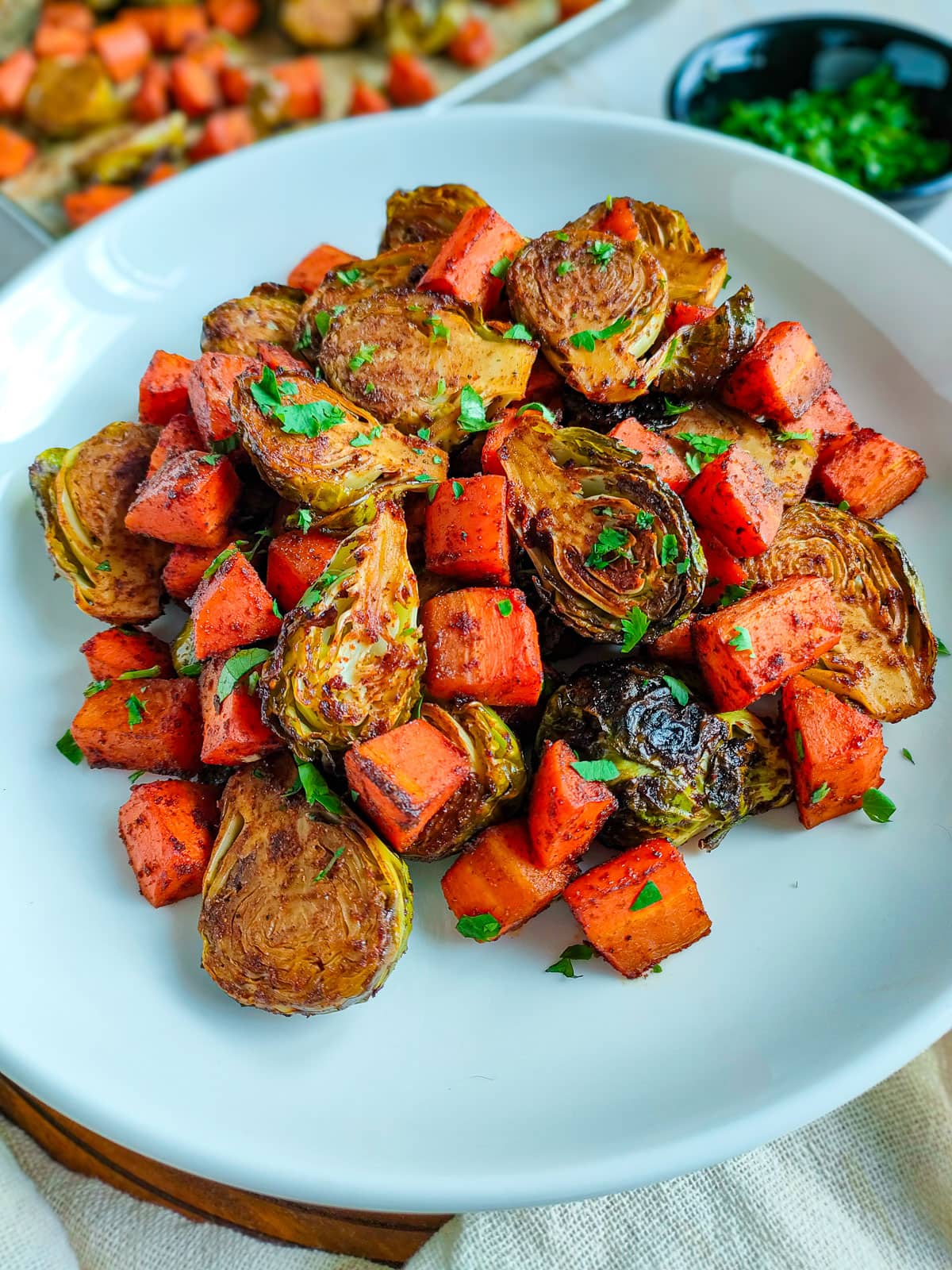 Oven roasted carrots and brussels sprouts on a whit plate.