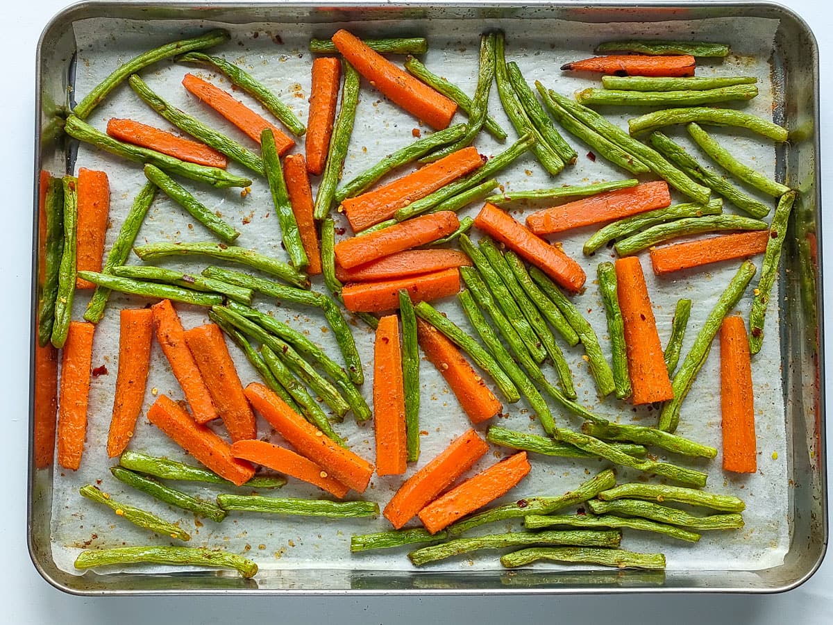 Roasted green beans and carrots on a large sheet pan.