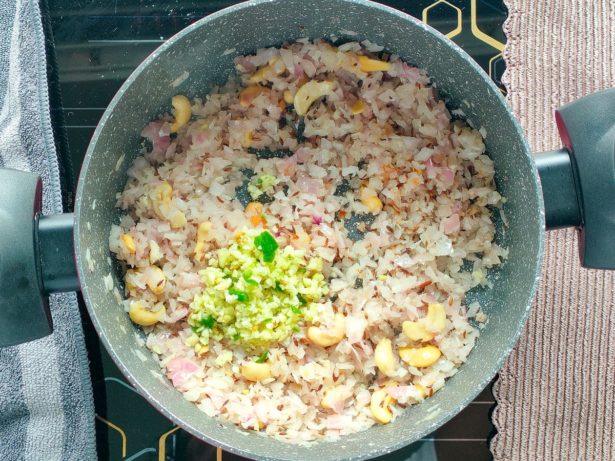 Ginger, garlic and onions with Cumin seeds and cashew nuts being sauteed in a pot.