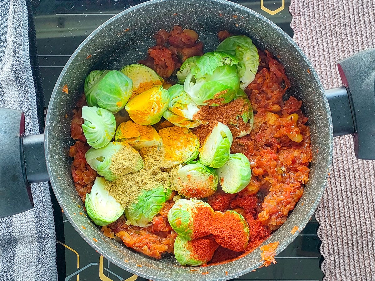 Brussels sprouts and spices with onion tomato paste in a curry pot.