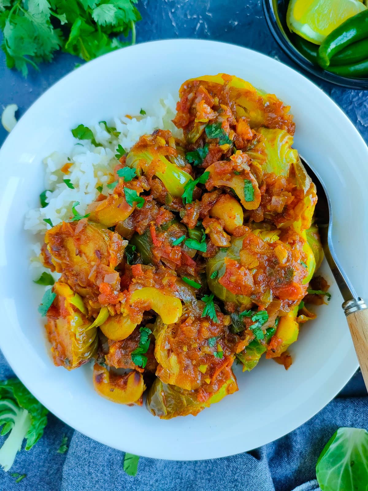 Curried Brussels sprouts with rice on a white plate with a spoon.