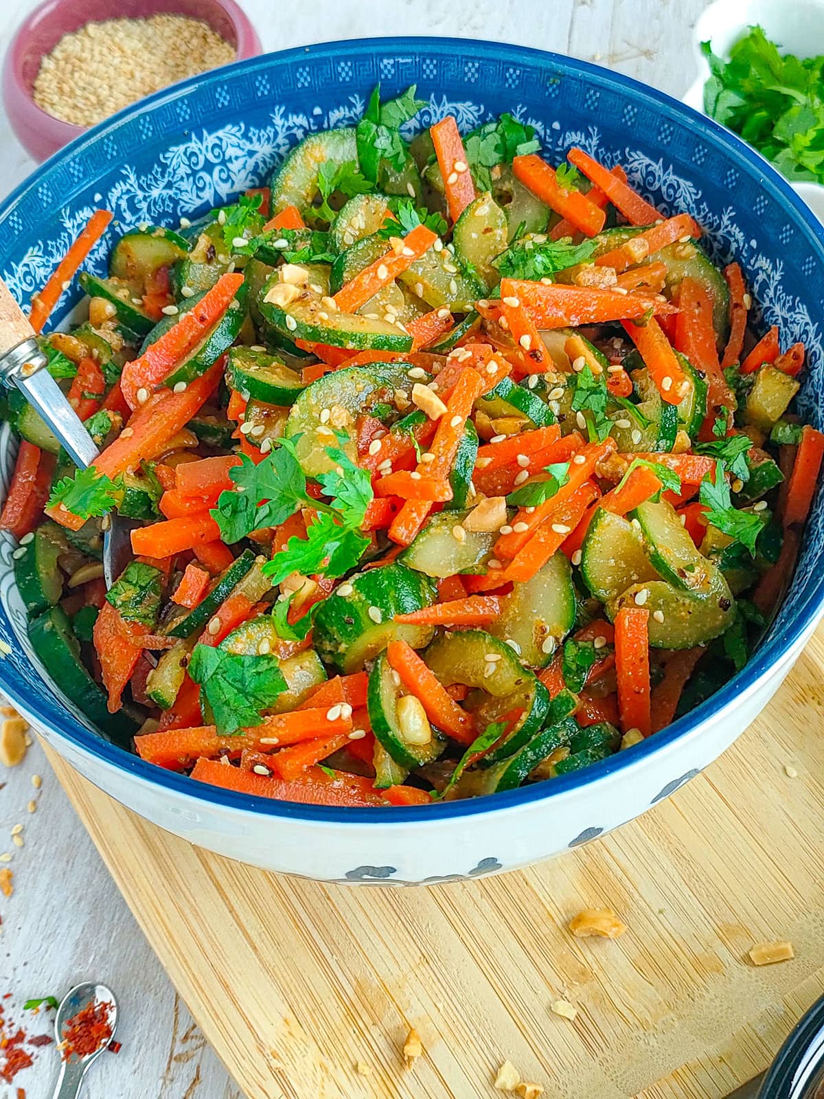 Asian cucumber carrot salad in a blue bowl with a spoon in it.