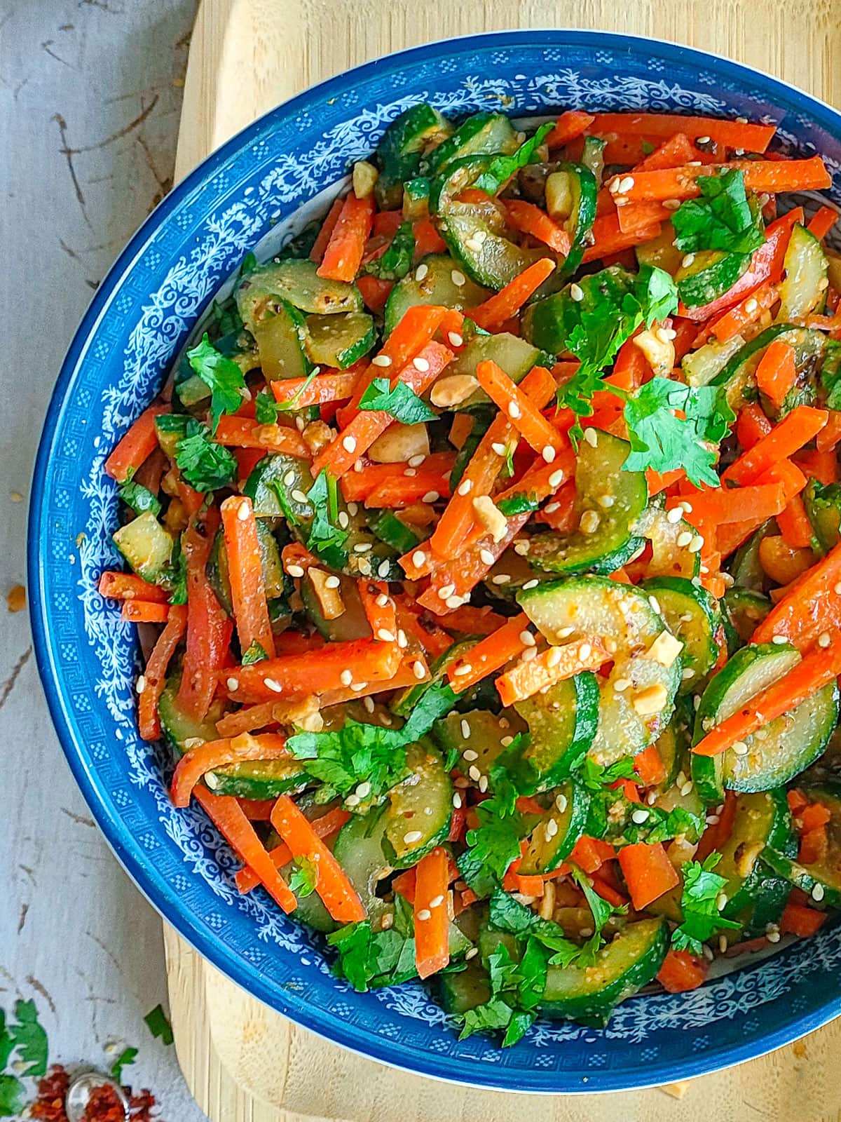 Asian carrot salad with cucumbers in a blue bowl.