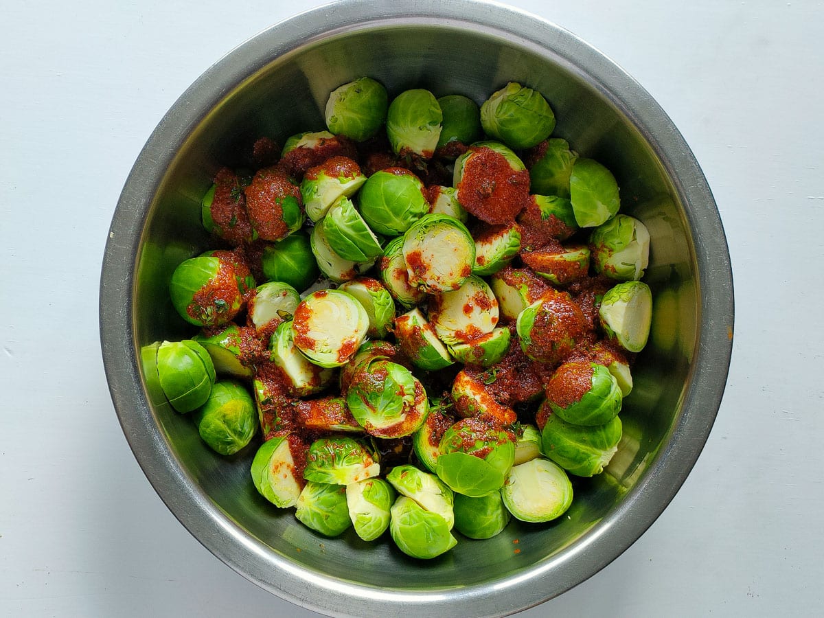 Brussels sprout halves with marinade in a large bowl.