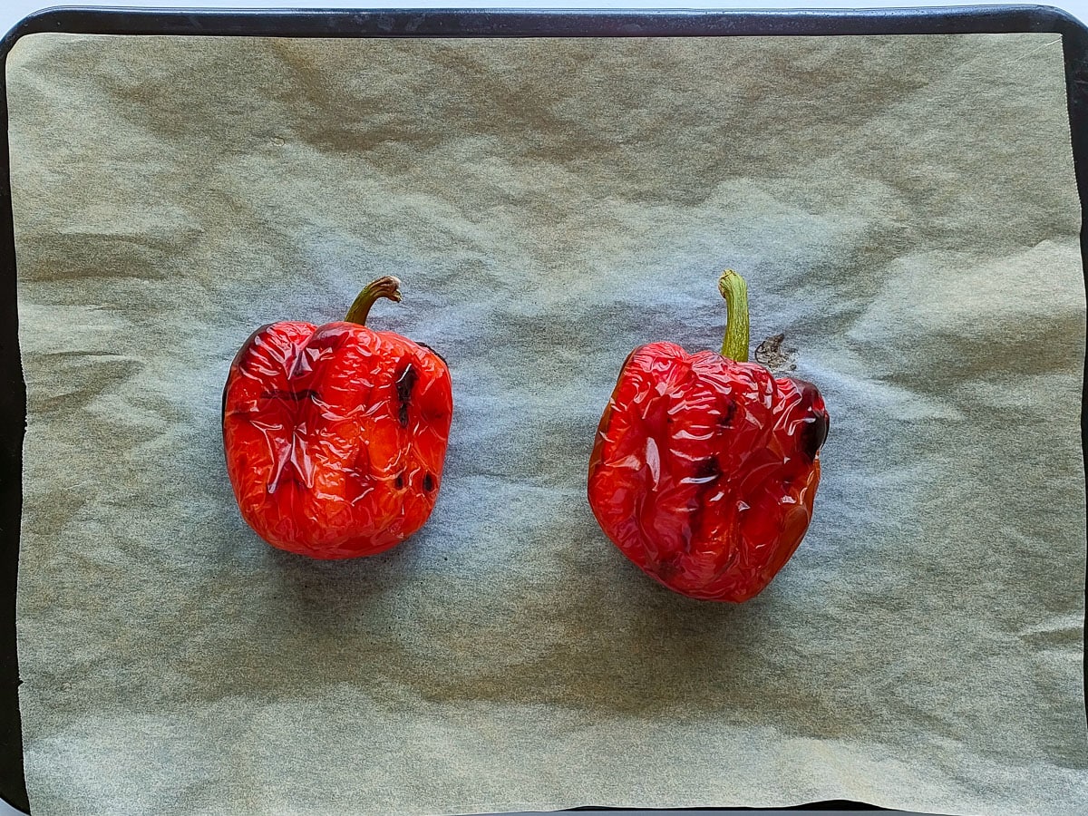 2 roasted red peppers on a baking sheet lined with parchment paper.
