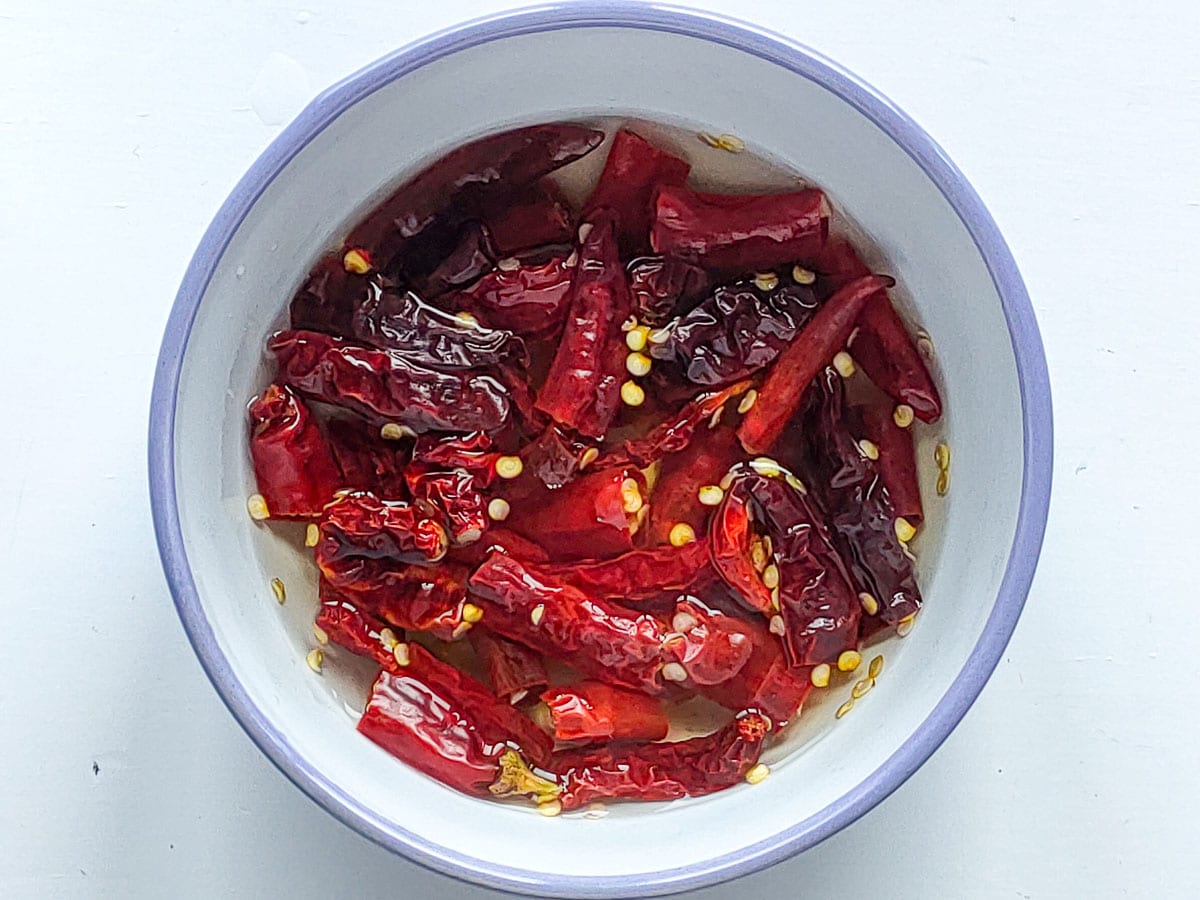 Chilies soaked in hot water in a white bowl.